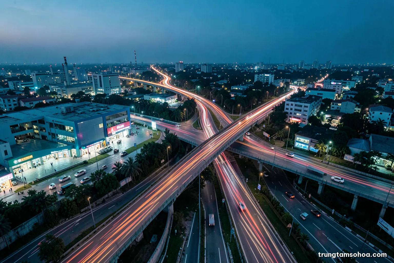 Aerial view at dusk of a Vietnamese highway interchange with streams of vehicle light trails splitting and merging, long exposure, deep blue and amber palette